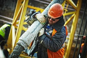 construction worker guiding a concrete applicator pipe