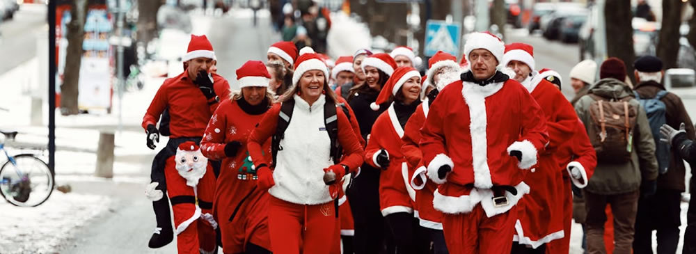 A group of people in Santa outfits walking on the street